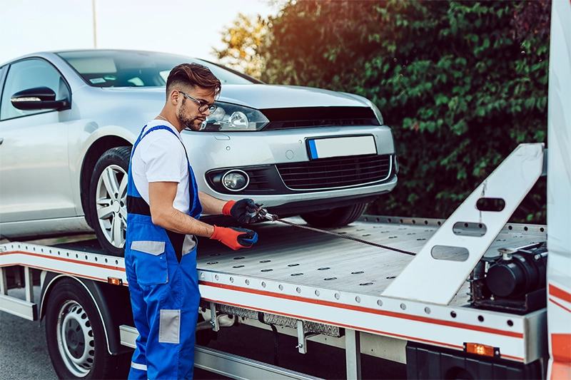 image of a car being put on a tow truck by a service man