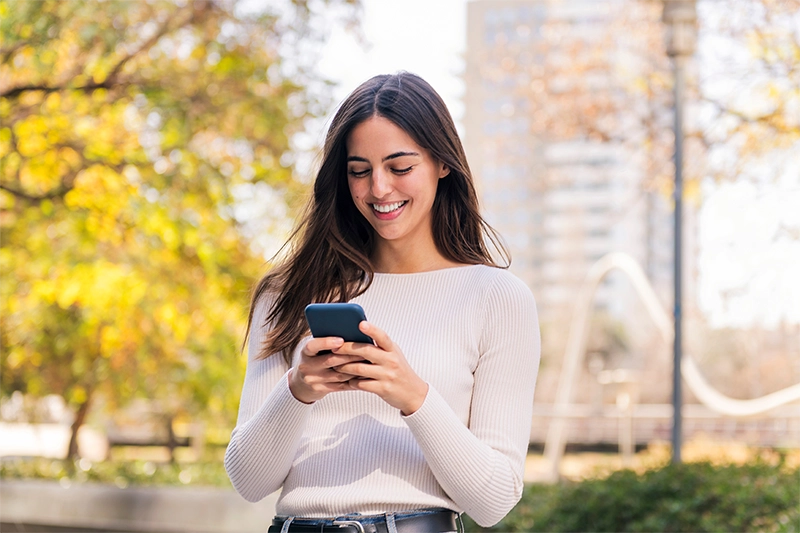 image of smiling women outside looking at her cell phone